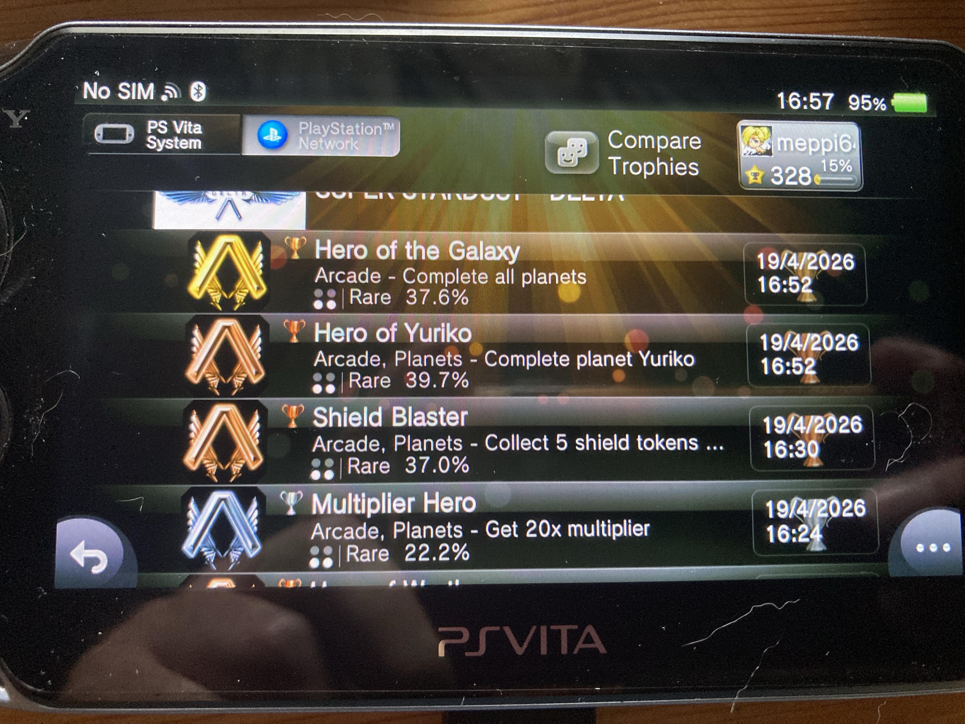 An image of a PlayStation Vita displaying trophy achievements for various arcade games. The trophies listed include "Hero of the Galaxy," "Hero of Yuriko," "Shield Blaster," and "Multiplier Hero," along with their completion statuses and rarity percentages.